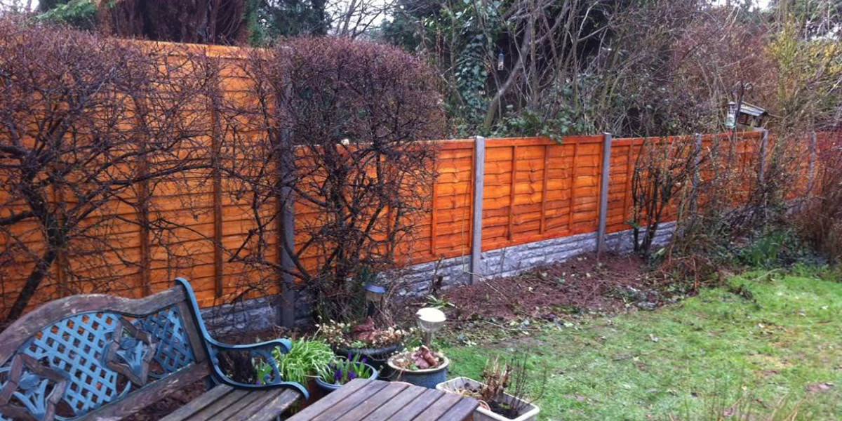 Concrete post with overlap panel fence and rock face gravel board